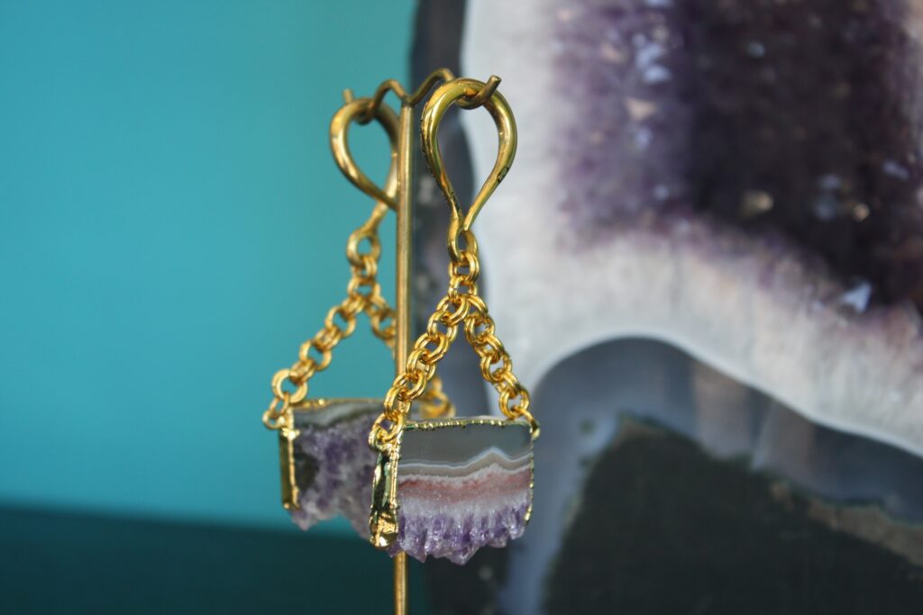A pair of earrings hanging from chains on a stick.