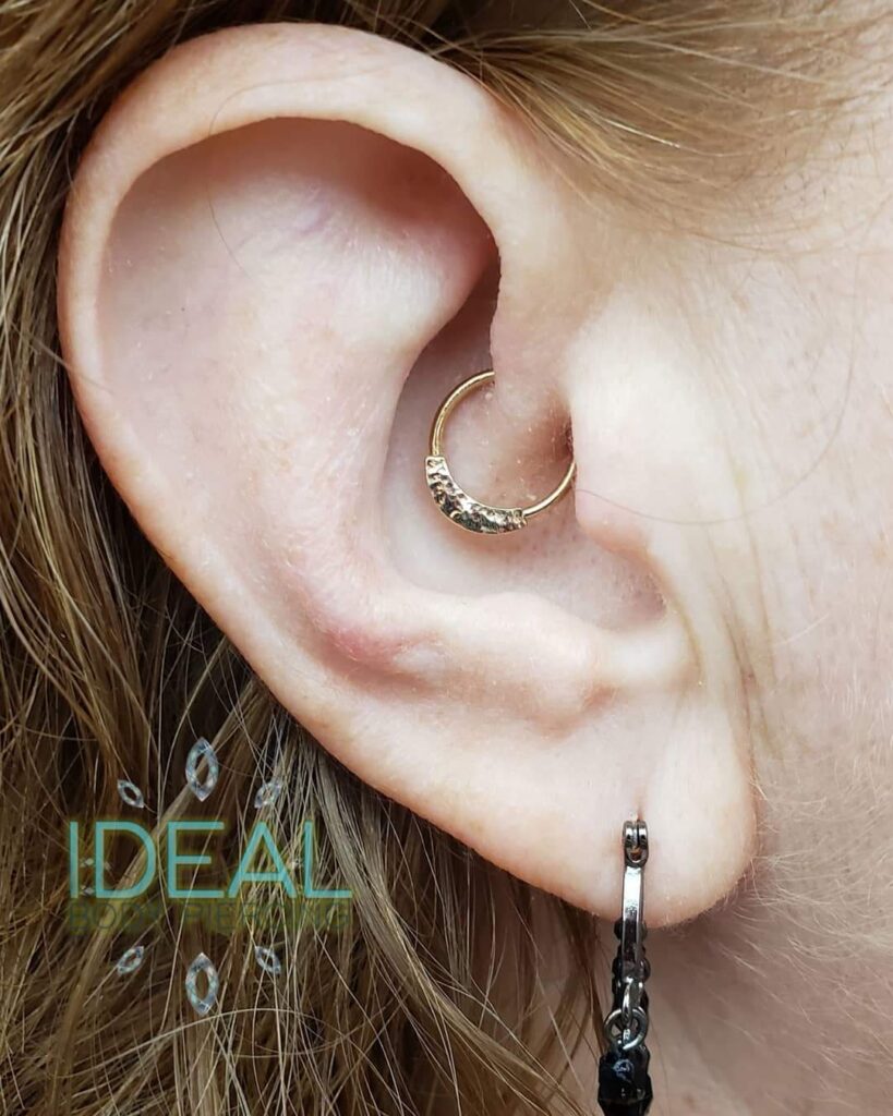 A woman wearing an ear piercing with the word " ideal " in front of her ear.