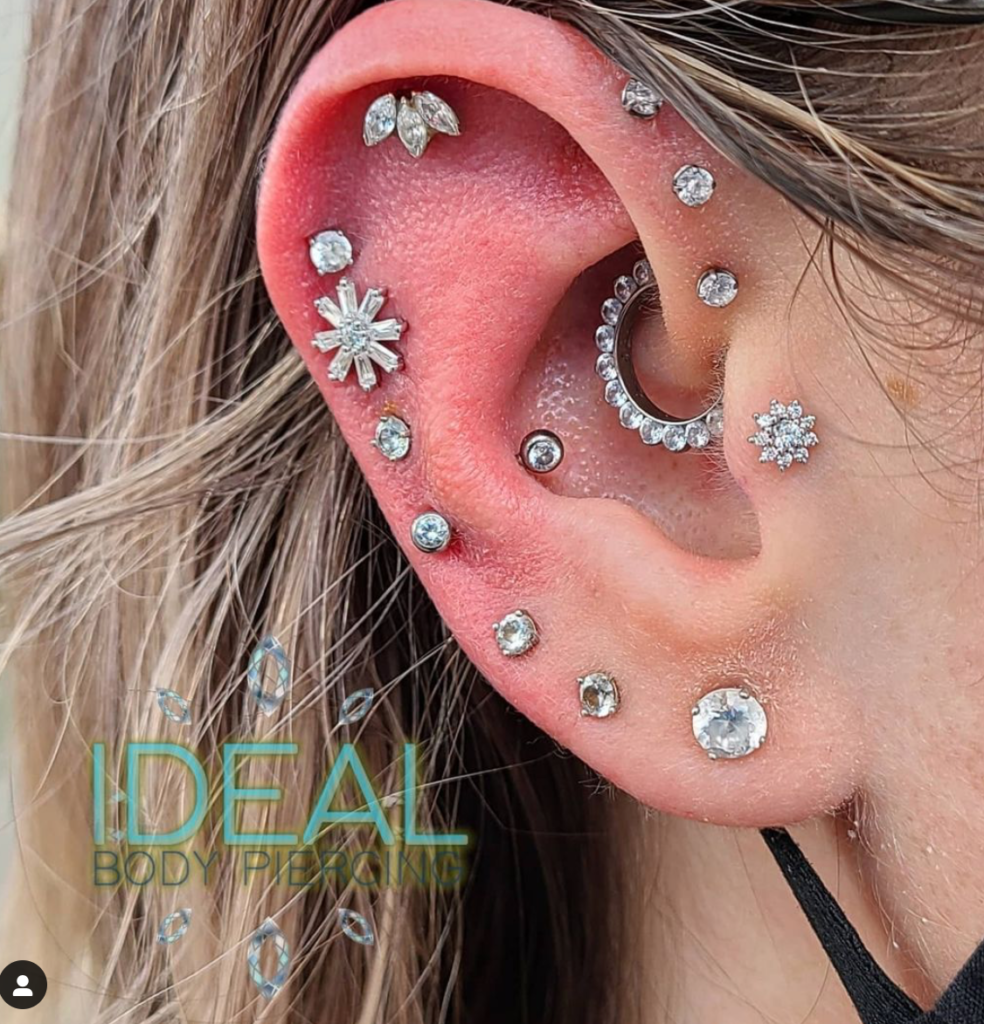 A woman 's ear with multiple piercings and a flower design.